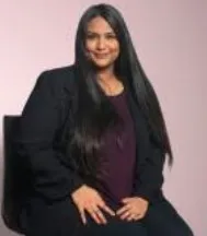 Anushka Iyer founder of Wiggles India seated dark jacket long dark hair light background